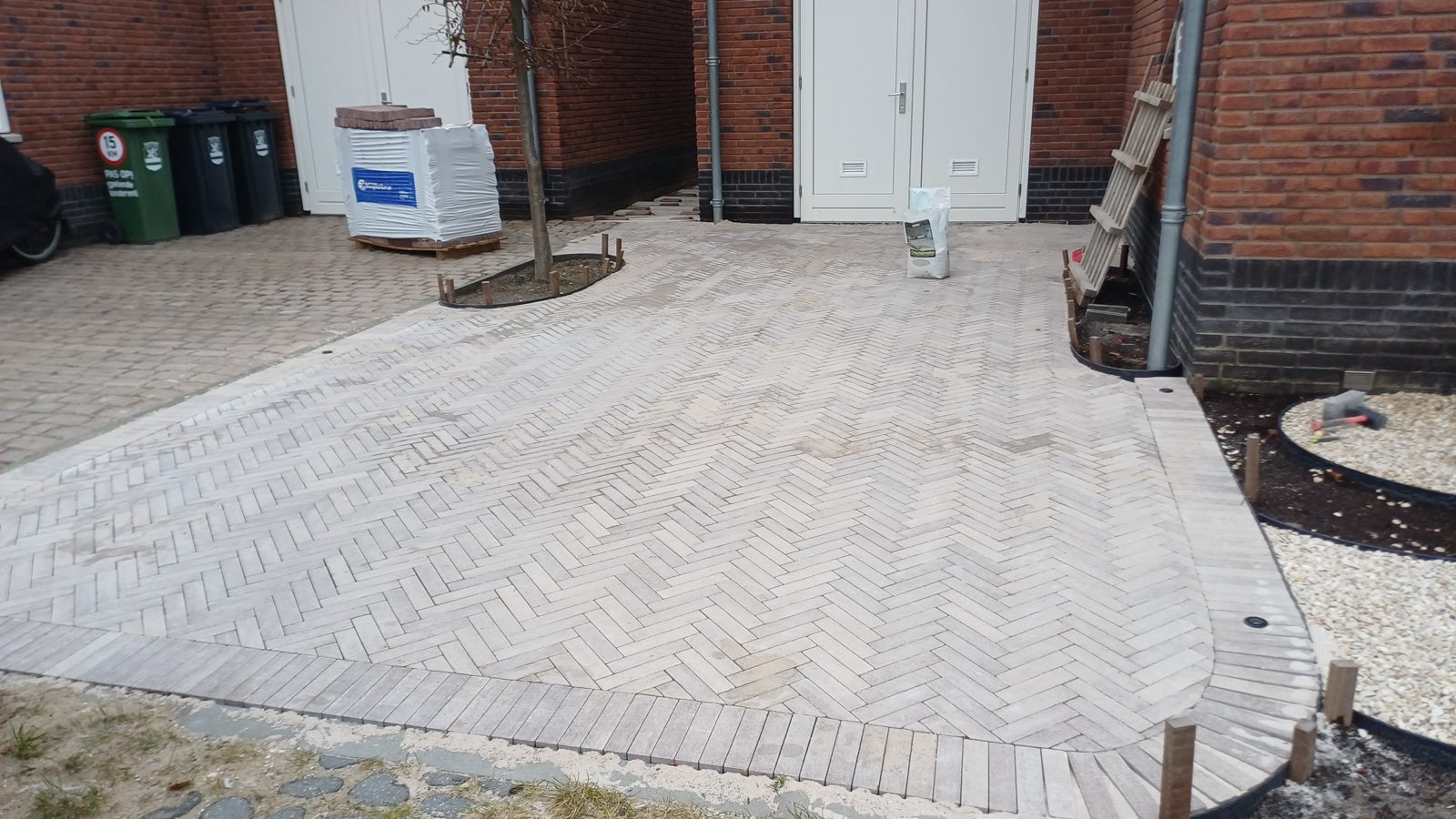 Groot terrein bestraat in beige keien in visgraatverband tussen bedrijfspanden