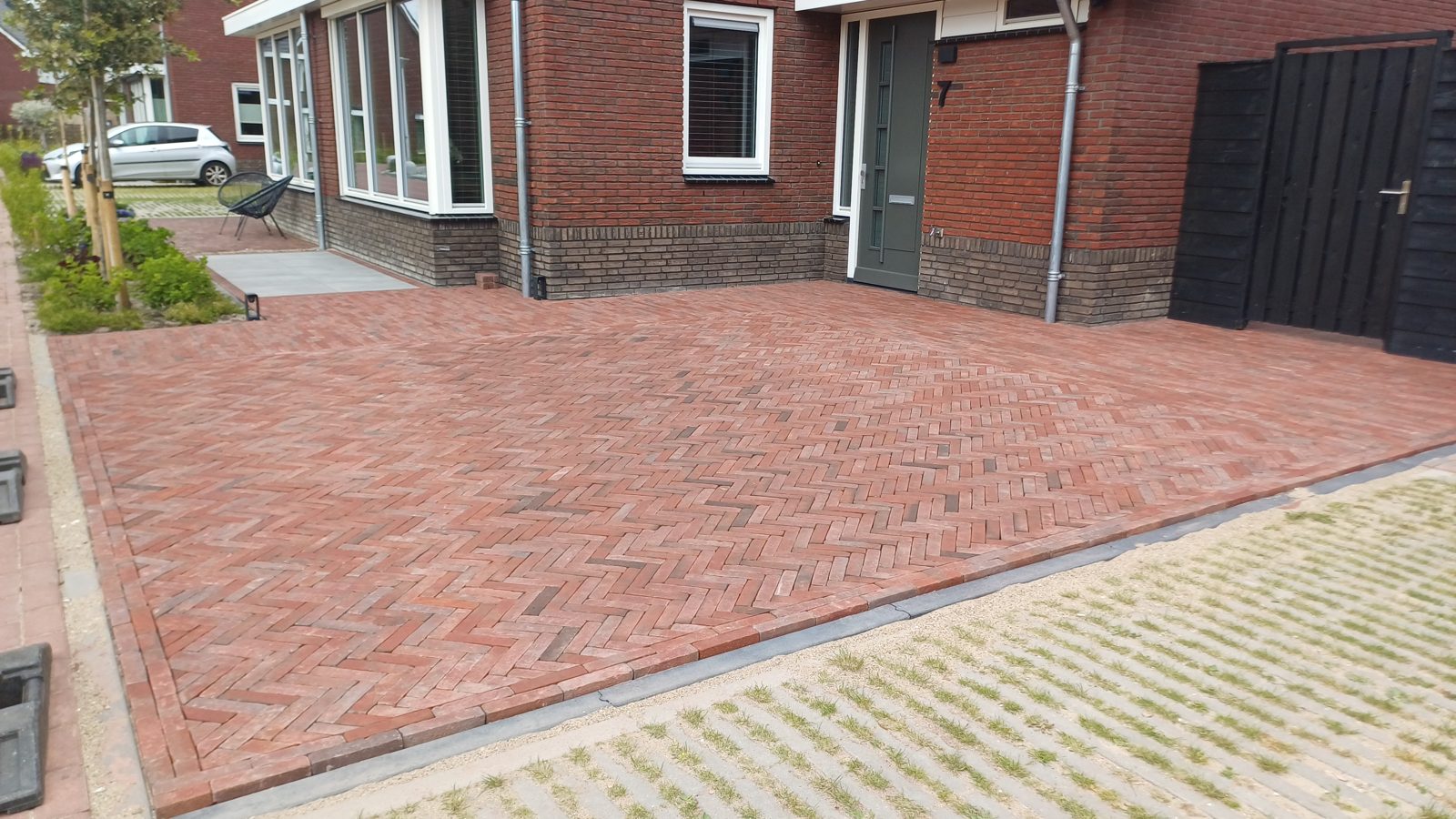 Strak aangelegde oprit in rode gebakken klinkers in visgraatverband voor een woning in het Westland