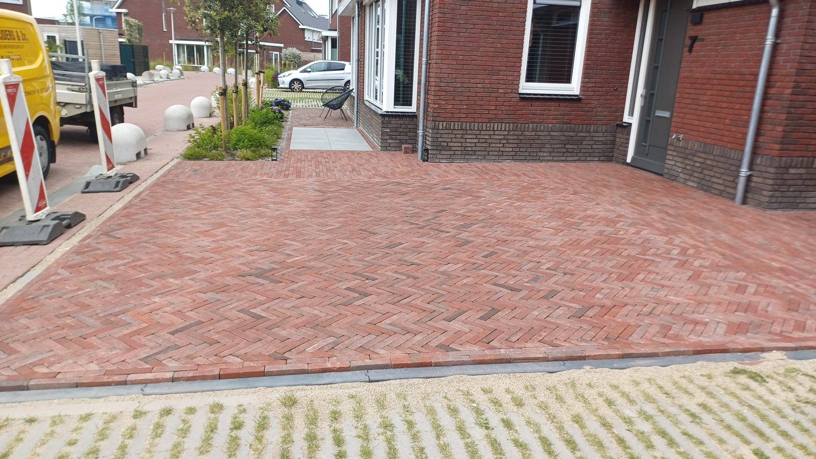 Oprit in rode gebakken klinkers in visgraatverband, met bedrijfsbus van A.A. Snijders langs de weg