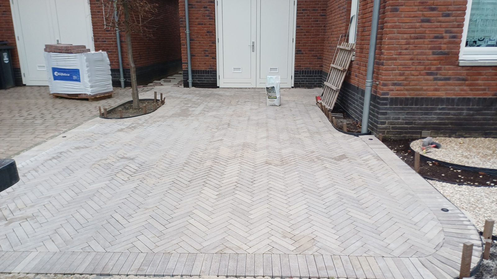 Groot bestraat parkeervlak in gebakken klinkers naast woningen